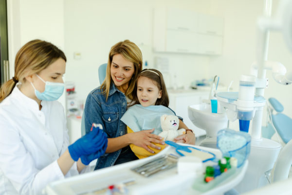 Happy mother and child seeing pediatric dentist.